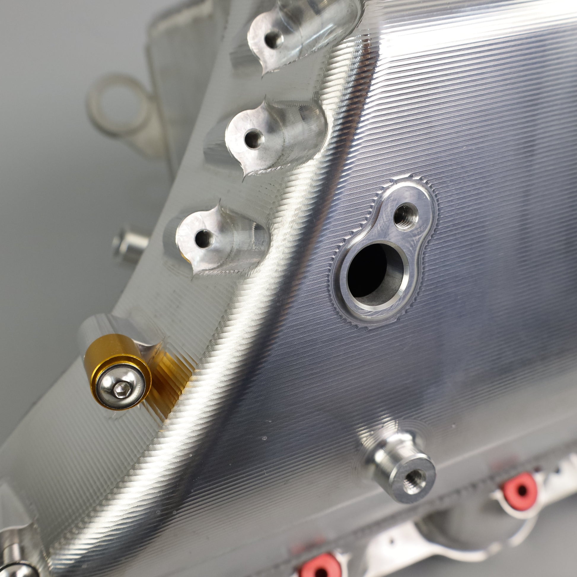 Close-up of a metallic engine cover with bolts on a gray background